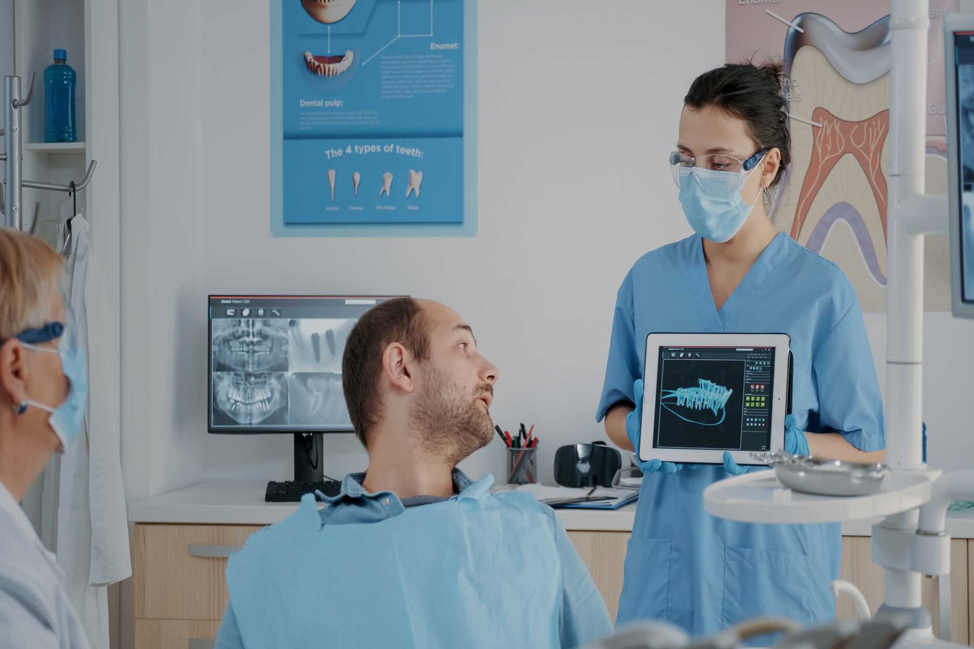 Team of dentists showing a patient their radiograph | Featured image for Does Getting Dentures Hurt - Does It Hurt to Get Dentures blog.