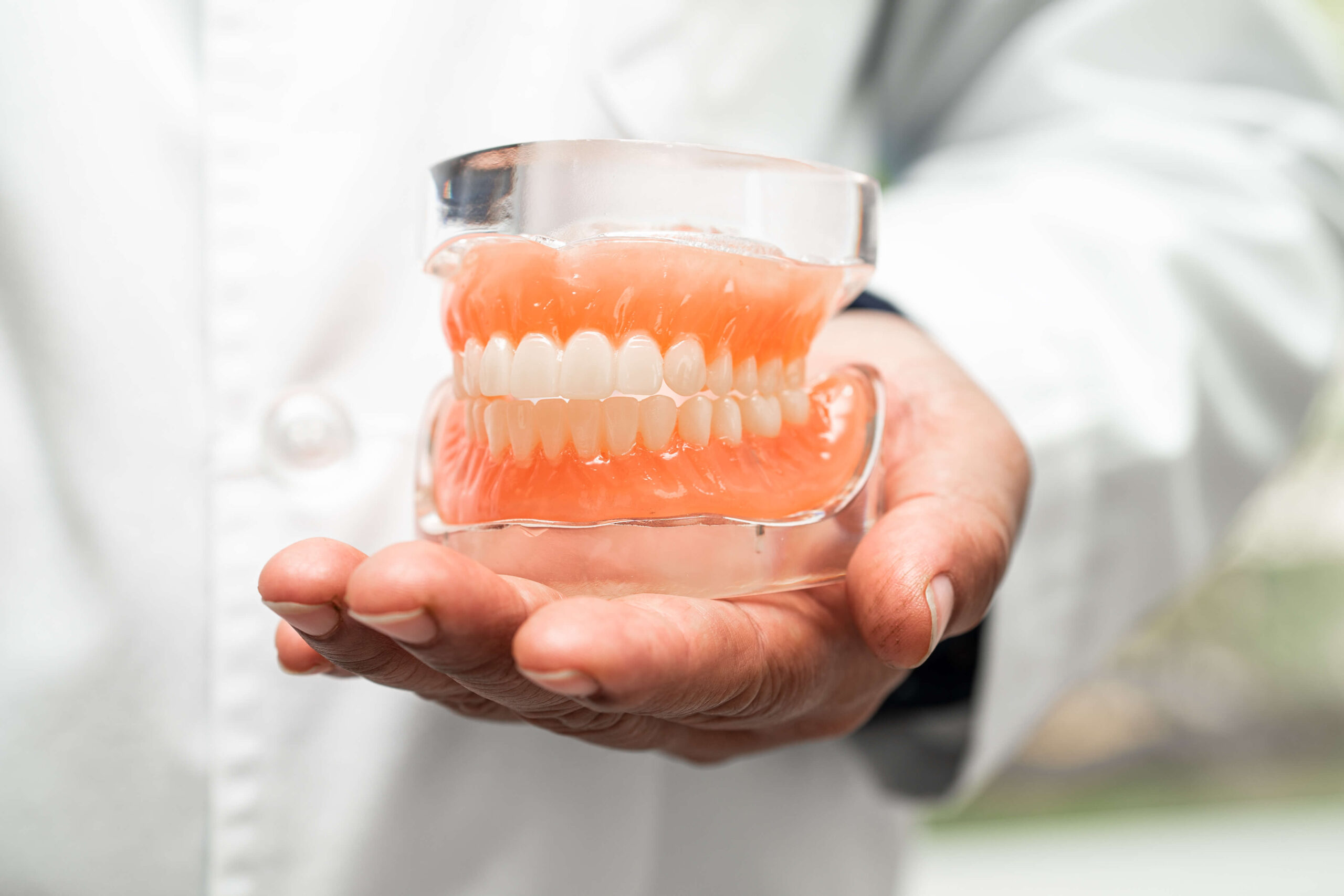 Dentist holding dentures | Featured image for the Playing with Dentures - A Guide for Musicians blog for Denture Health Care.